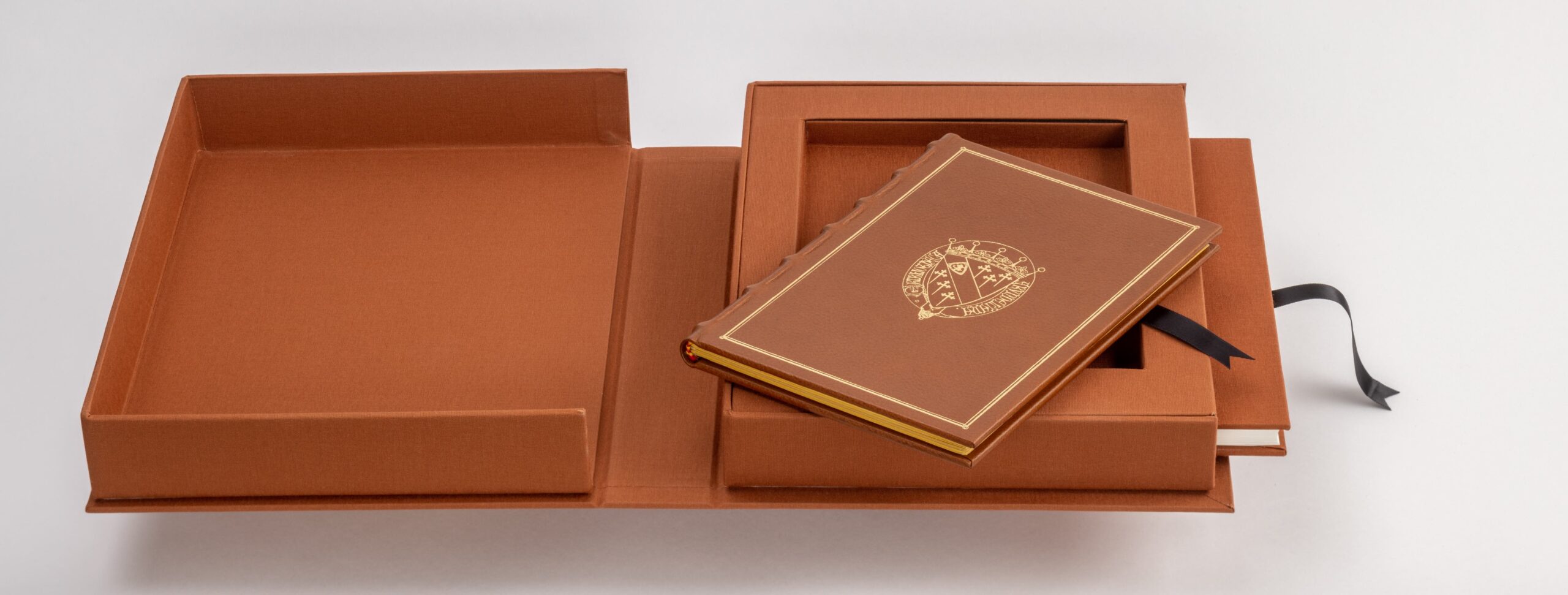 Facsimile edition of the Tabula Cebetis with open decorative cassette. The facsimile with gold-embossed leather binding lies diagonally on the cassette.