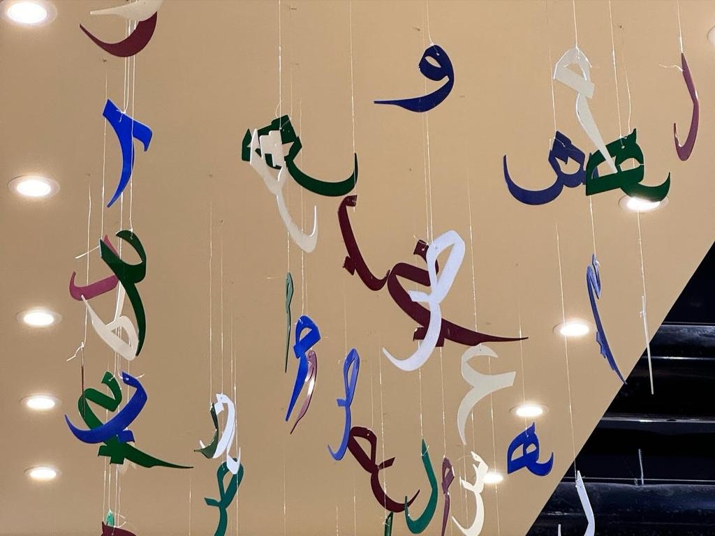 Messeeindrücke von der Buchmesse in Riad. Fliegende arabische Schriftzeichen hängen von der Decke.