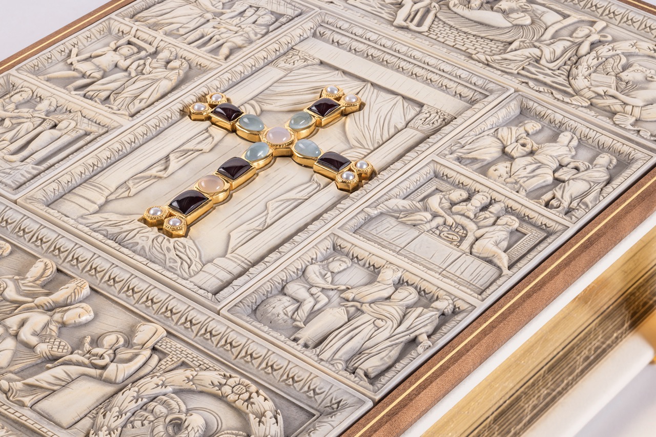 Bildausschnitt des Einbands mit Fokus auf dem in der Mitte liegenden echtvergoldeten Prachtkreuz besetzt mit Edelsteinen.